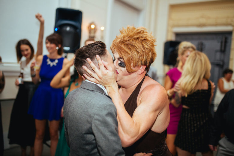Person in suit kissing person in drag