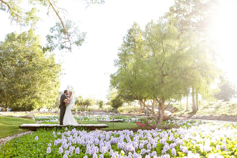 Bride and groom kissing in garden with flowers