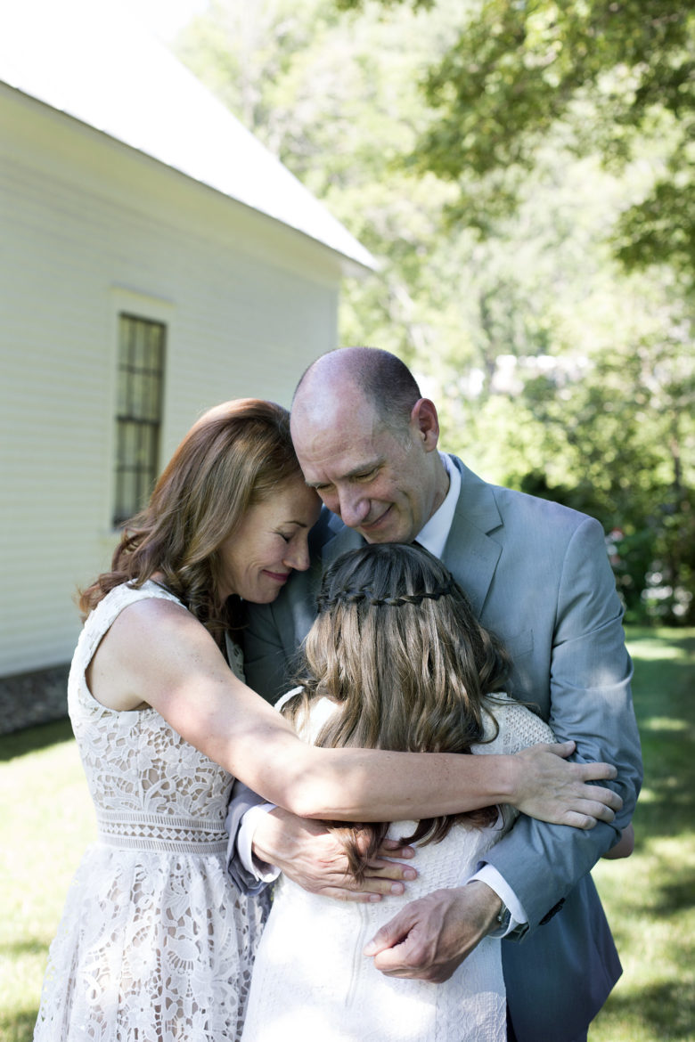 Bride and groom hugging daughter