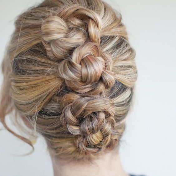 woman with honey, blond, and brown hair pulled back into four braided buns, vertically along back of head