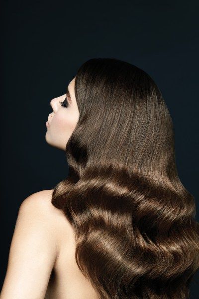 woman with very shiny, sleek, long dark hair with waves starting around shoulder height 