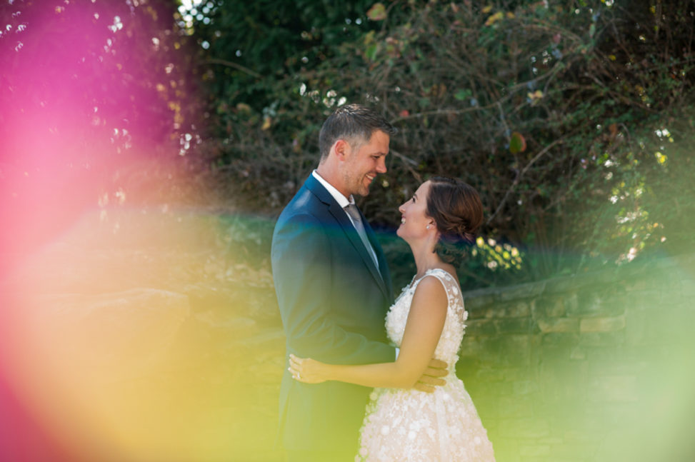 bride and groom embracing and smiling with colorful lens flare